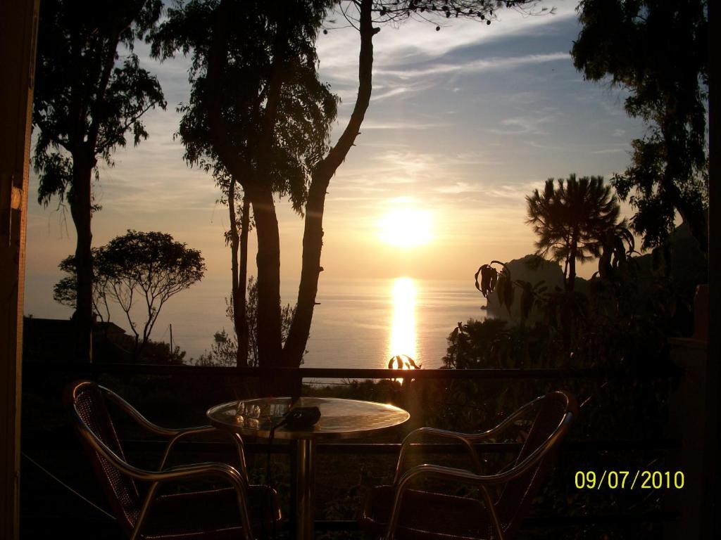 una mesa y sillas con la puesta de sol en el fondo en Ermones Mare, en Ermones