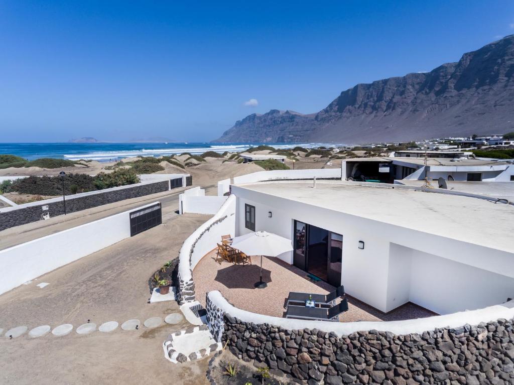 a white house on the beach with a stone wall at Famara House 12 in Famara