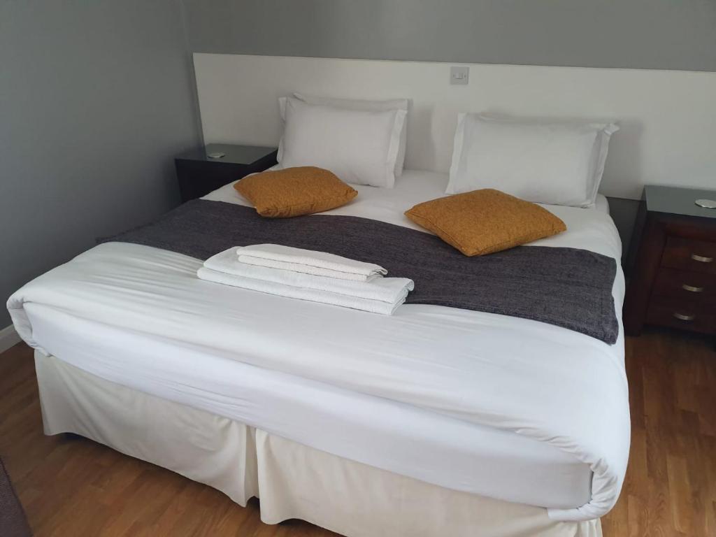 un grande letto bianco con due cuscini sopra di Watts Lodge a Bicester
