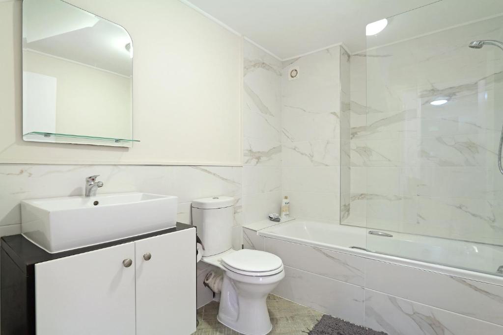 a white bathroom with a toilet and a sink and a tub at G Zero 3 @ The Breakers in Hout Bay