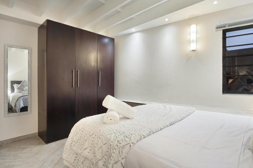 a bedroom with a white bed with a wooden cabinet at G Zero 3 @ The Breakers in Hout Bay