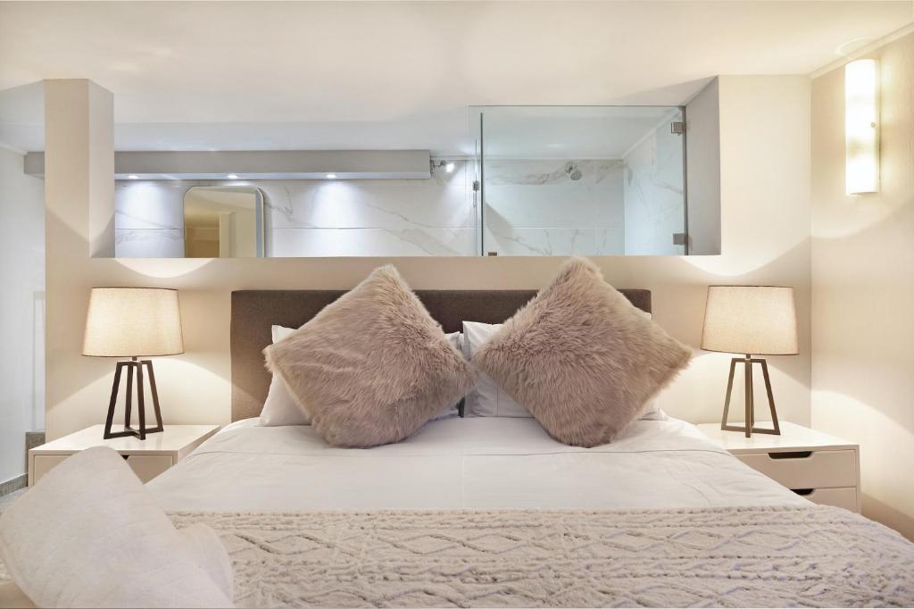 a bedroom with a bed with two lamps and a mirror at G Zero 3 @ The Breakers in Hout Bay