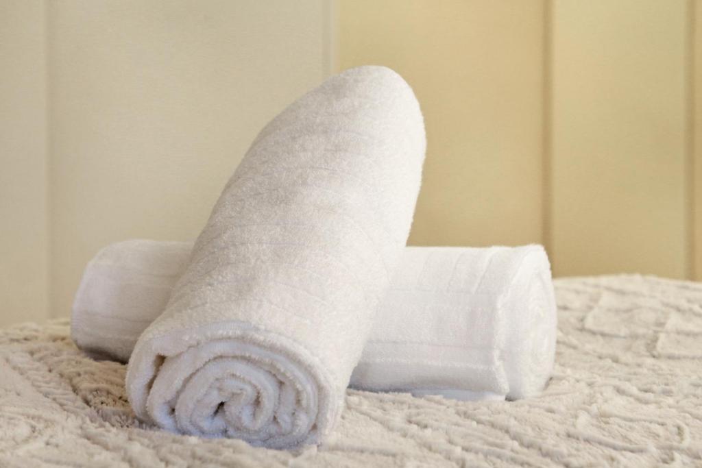 a roll of white towels sitting on a bed at G Zero 3 @ The Breakers in Hout Bay