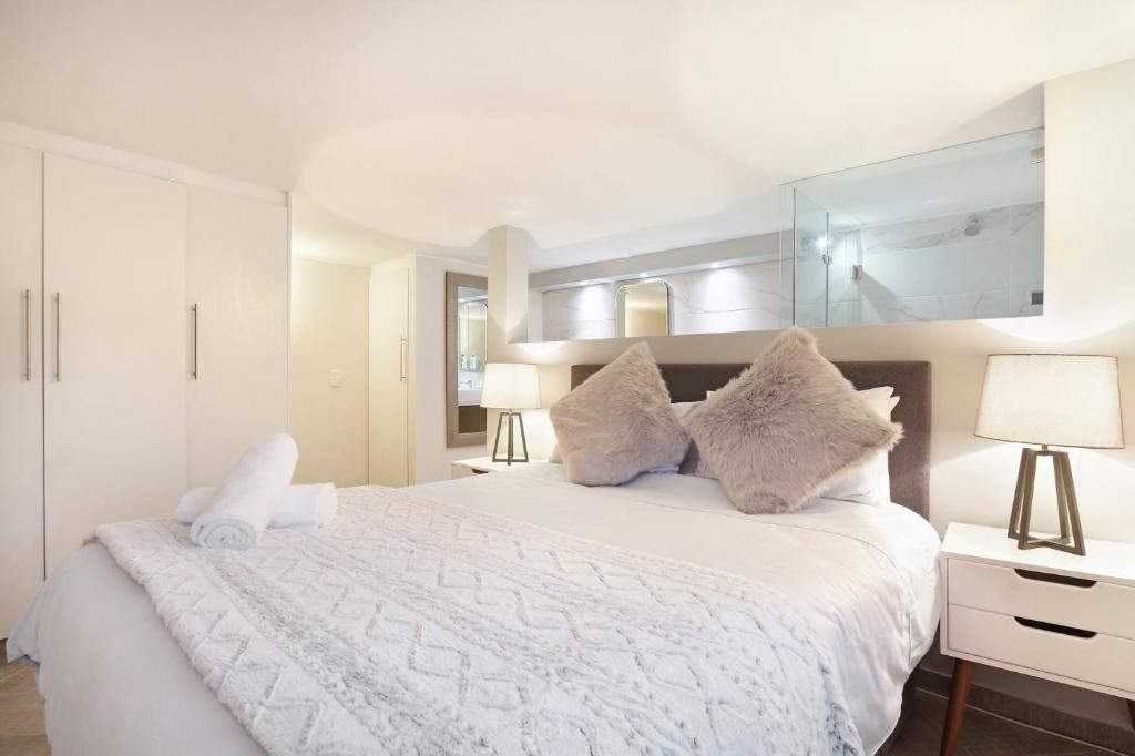 a white bedroom with a large white bed with pillows at G Zero 3 @ The Breakers in Hout Bay