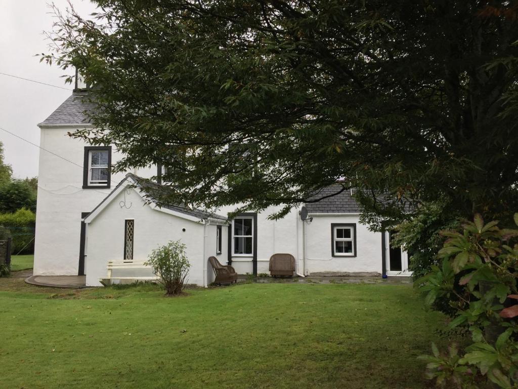 Una casa blanca con un árbol delante. en Kilmory House, en Lochgilphead