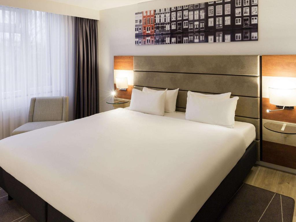 
a hotel room with a large bed and a large window at Mercure Hotel Amsterdam West in Amsterdam
