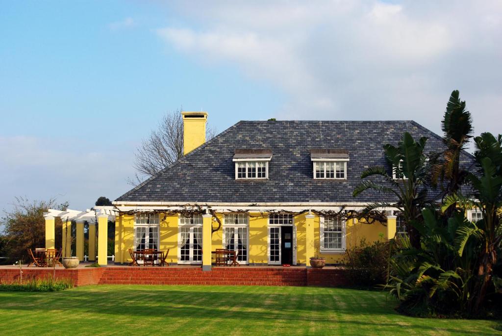 ein gelbes Haus mit einem schwarzen Dach und einem Hof in der Unterkunft Lyngrove Wines & Guesthouse in Stellenbosch