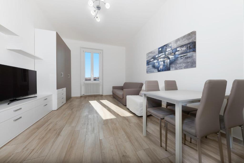 Biały salon ze stołem i telewizorem w obiekcie Casa da Suite Hora w Mediolanie