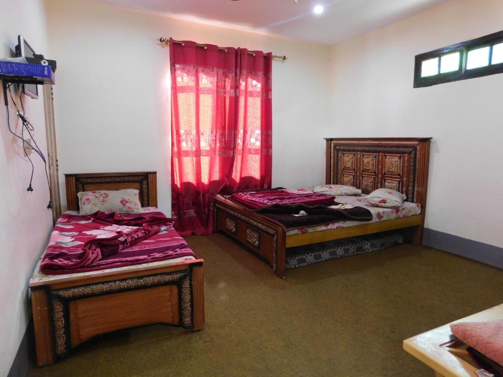 duas camas num quarto com cortinas vermelhas em Mountain View Hotel em Bālākot