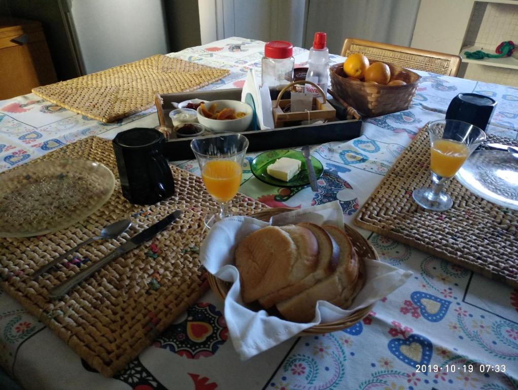 un tavolo con un cesto di pane e bicchieri di succo d'arancia di Dormitorios La Lucila Vicente Lopez Sol & Tren a La Lucila