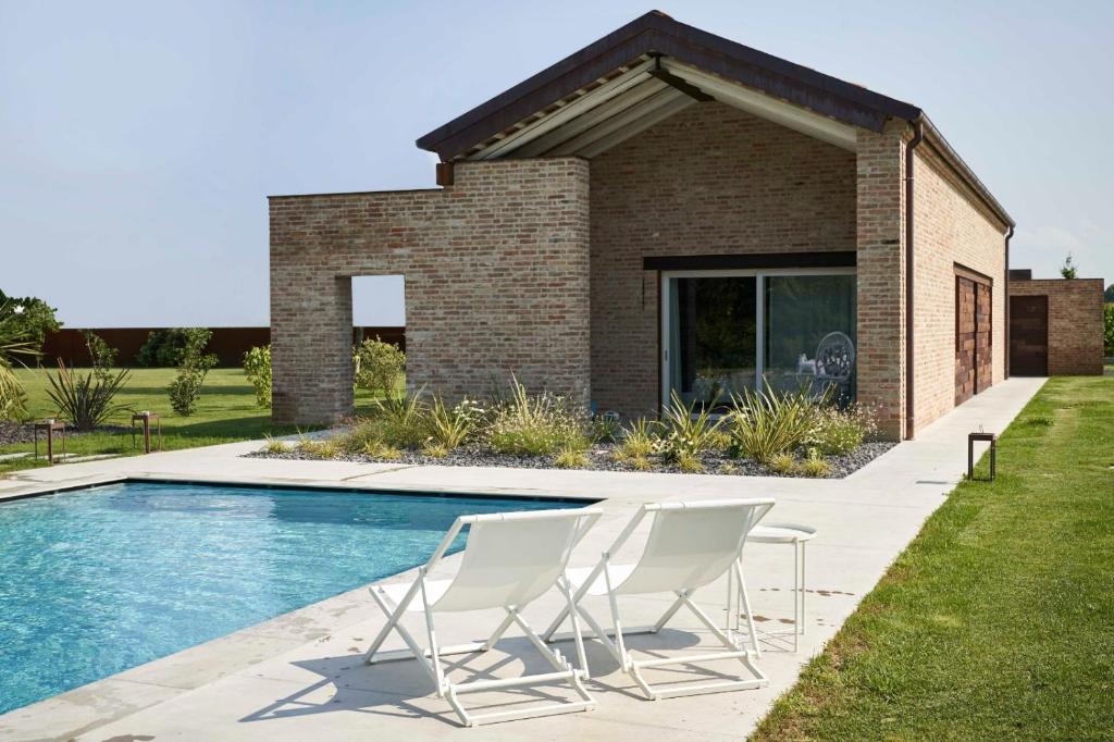 2 sillas y una piscina frente a una casa en B&B BARCO41, en SantʼAngelo di Piove di Sacco