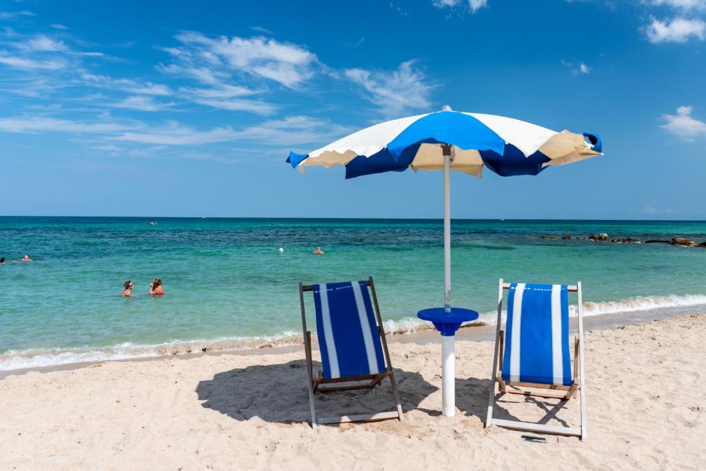 two chairs and an umbrella on the beach at Racar Hotel in Frigole