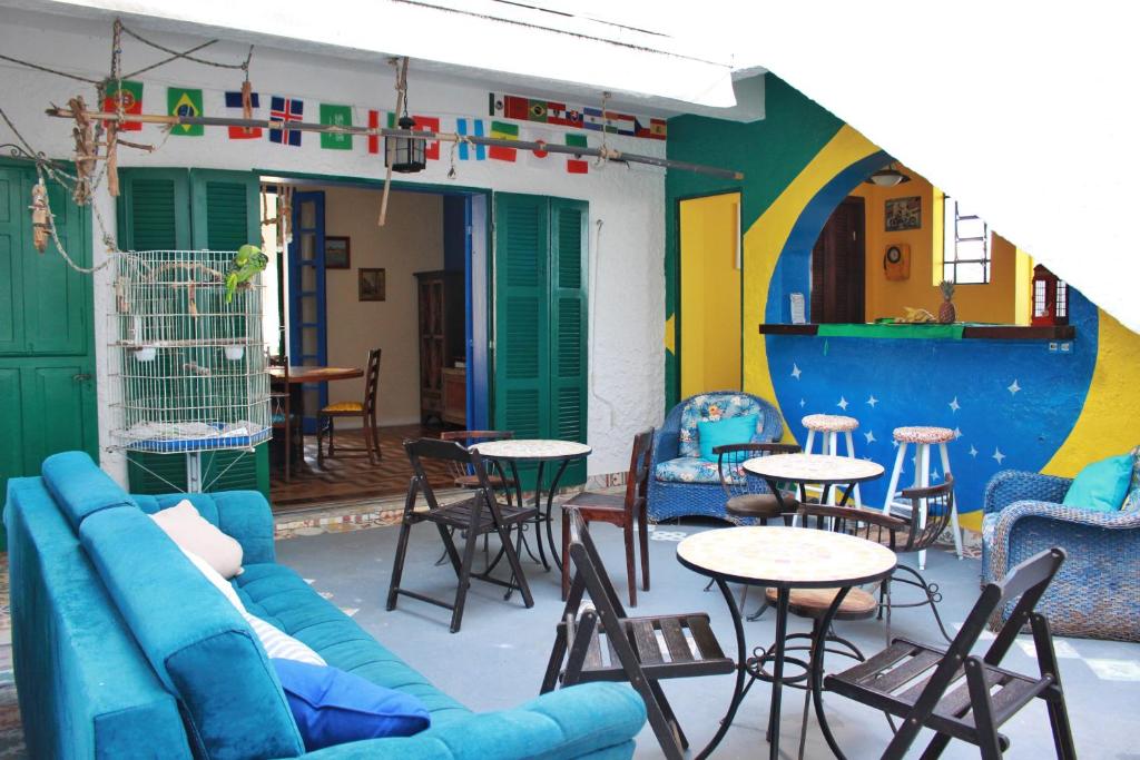 eine Terrasse mit einem Sofa, Tischen und Stühlen in der Unterkunft Hostel Maresias do Leme in Rio de Janeiro