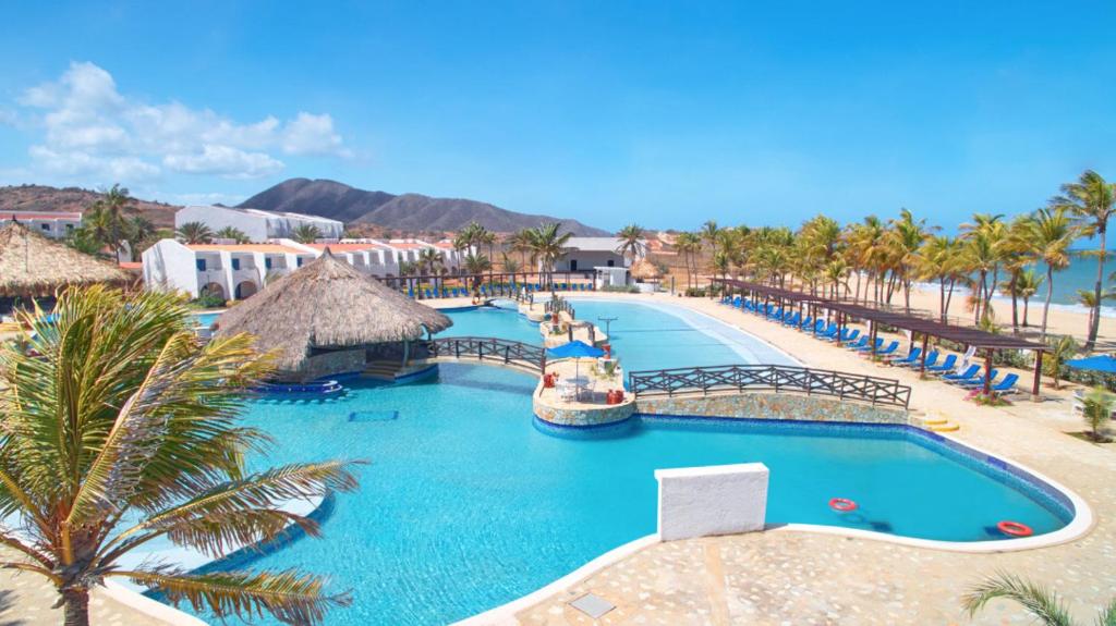 a pool at a resort with a boat in it at Costa Caribe Hotel Beach & Resort in La Galera