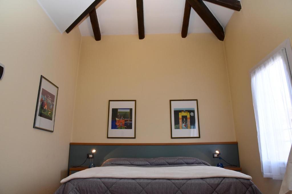 a bedroom with a bed and three pictures on the wall at Residence Al Bacareto in Mogliano Veneto