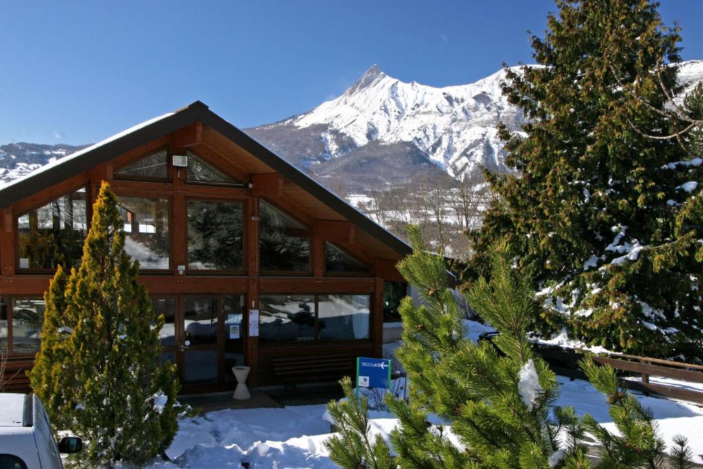ein Blockhaus mit einem schneebedeckten Berg im Hintergrund in der Unterkunft VVF Les Ecrins Champsaur in Saint-Bonnet-en-Champsaur