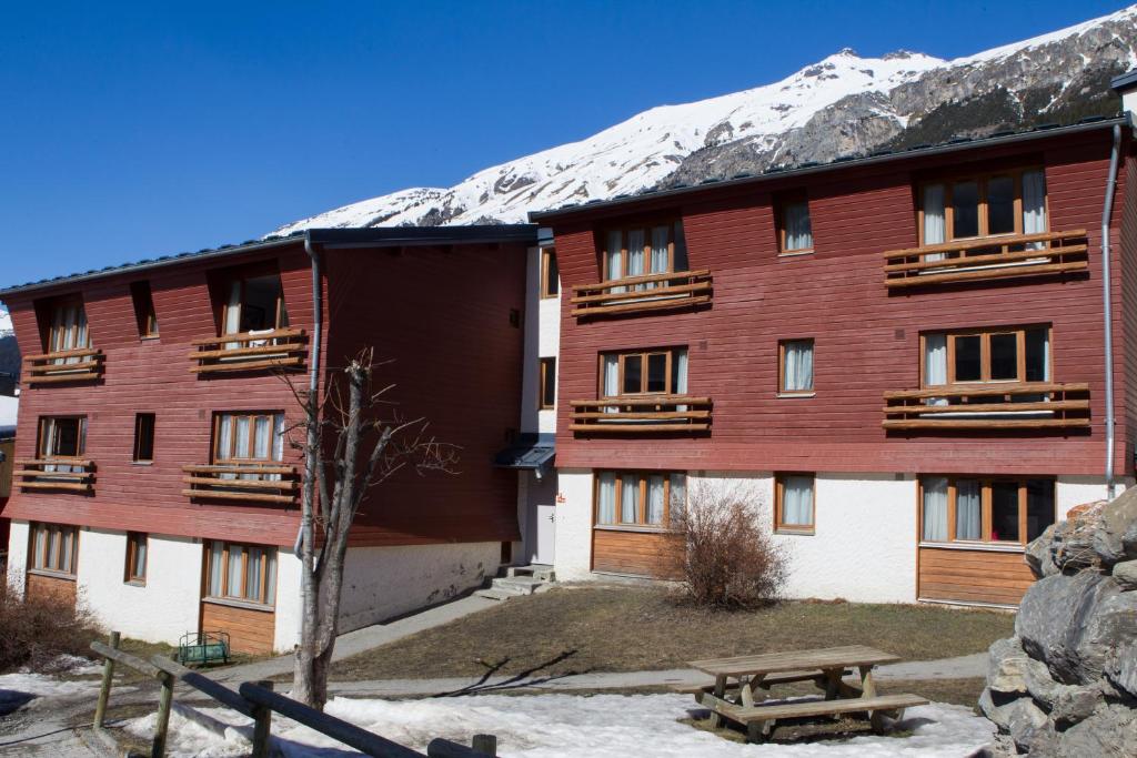 un gran edificio rojo con una montaña cubierta de nieve en VVF Val-Cenis Haute-Maurienne, en Lanslevillard