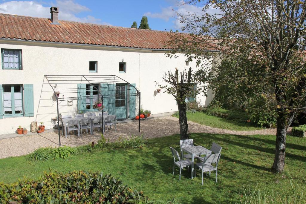 einen Garten mit Tischen und Stühlen vor einem Gebäude in der Unterkunft Gite Lumiere - hameau calme 8km de Jonzac in Nieul-le-Virouil