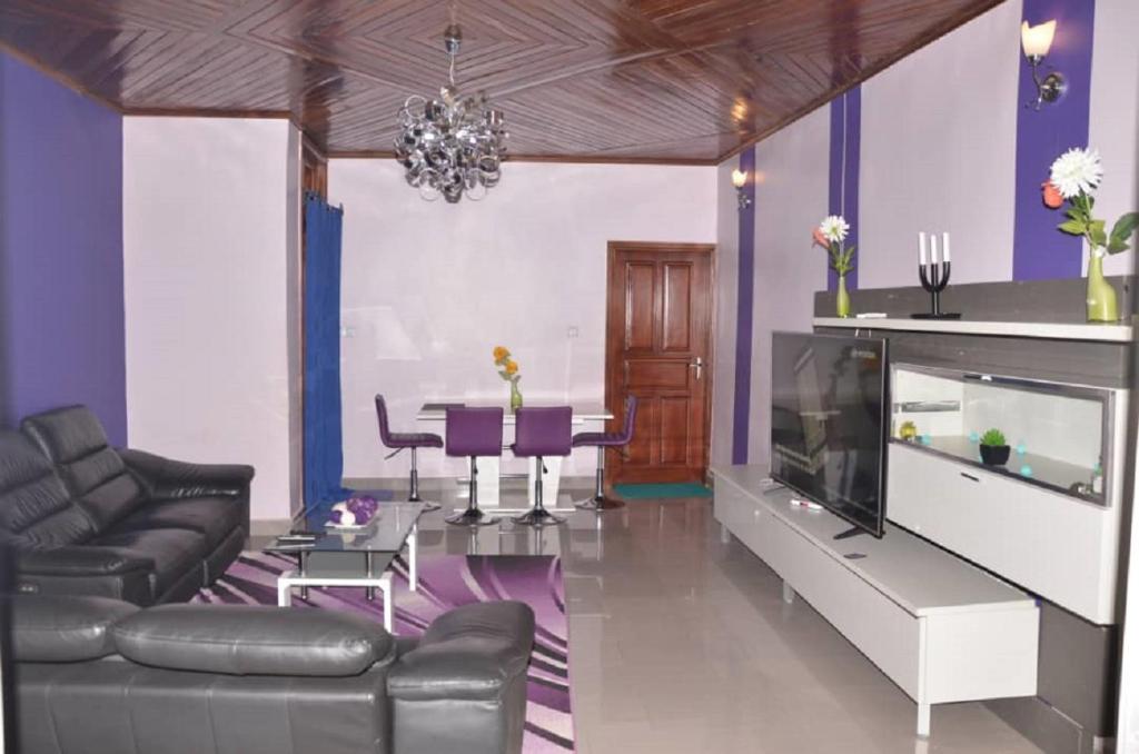a living room with a couch and a television and a table at Appart meublés Yaounde in Yaoundé
