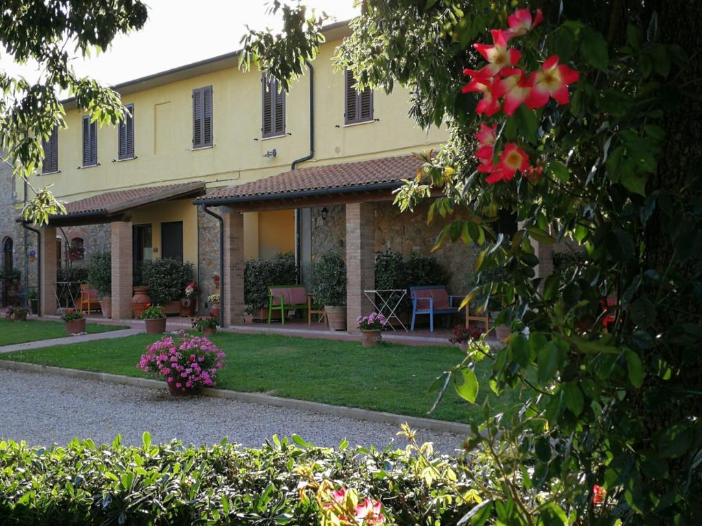 a large yellow building with a yard with flowers at Agriturismo Il Cuscino Nel Pagliaio in Campiglia Marittima