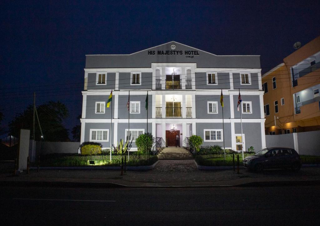 a white building with a sign on it at night at His Majesty's Hotel and Apartments in Accra