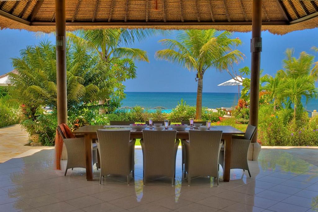 una mesa y sillas en un patio con vistas al océano en Villa Mawar, en Pengastulan