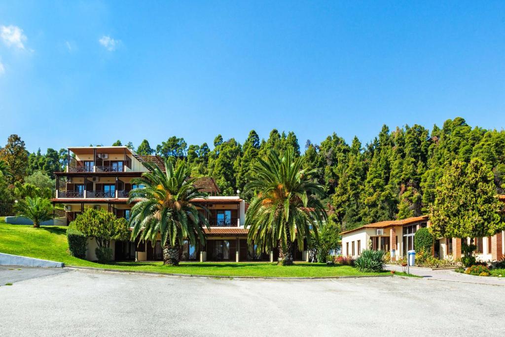 a house with palm trees in front of a road at Palladium Hotel in Kriopigi