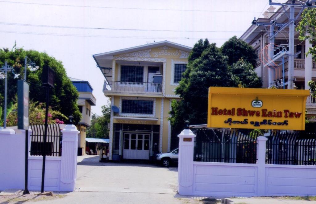 ein Haus mit einem gelben Schild auf einem Zaun in der Unterkunft Hotel Shwe Eain Taw in Yangon