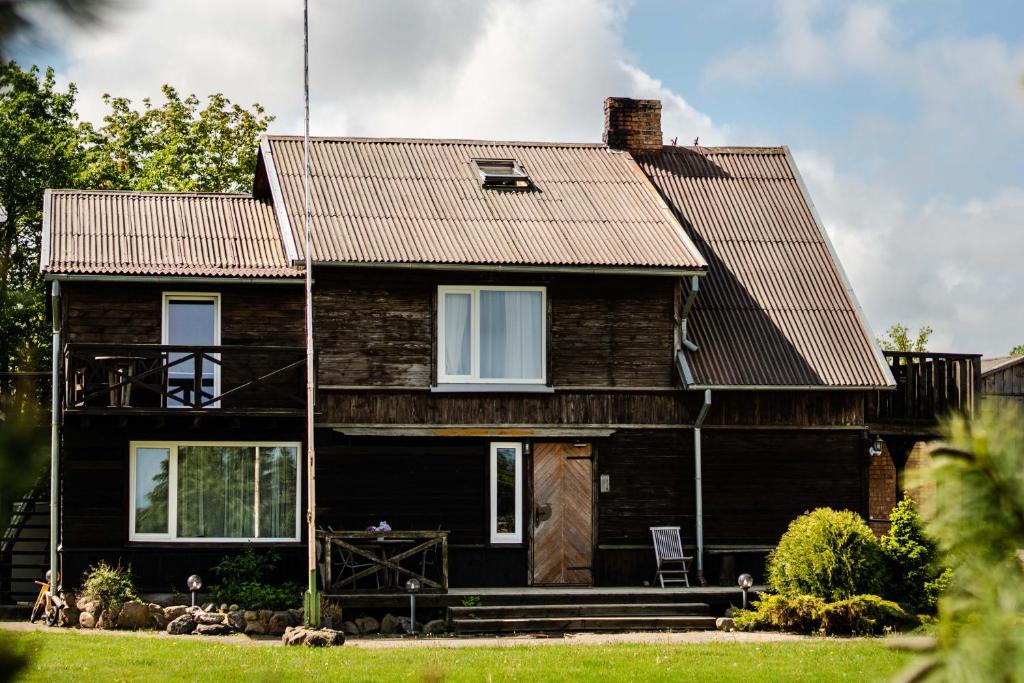 une maison noire avec un toit brun dans l'établissement Dandzenieki, à Pāvilosta