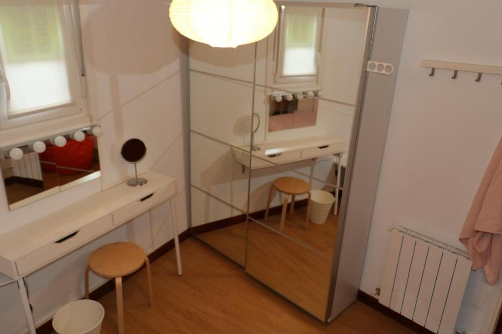 baño con espejo, lavabo y 2 taburetes en Acogedora Habitación Centro Bilbao, en Bilbao