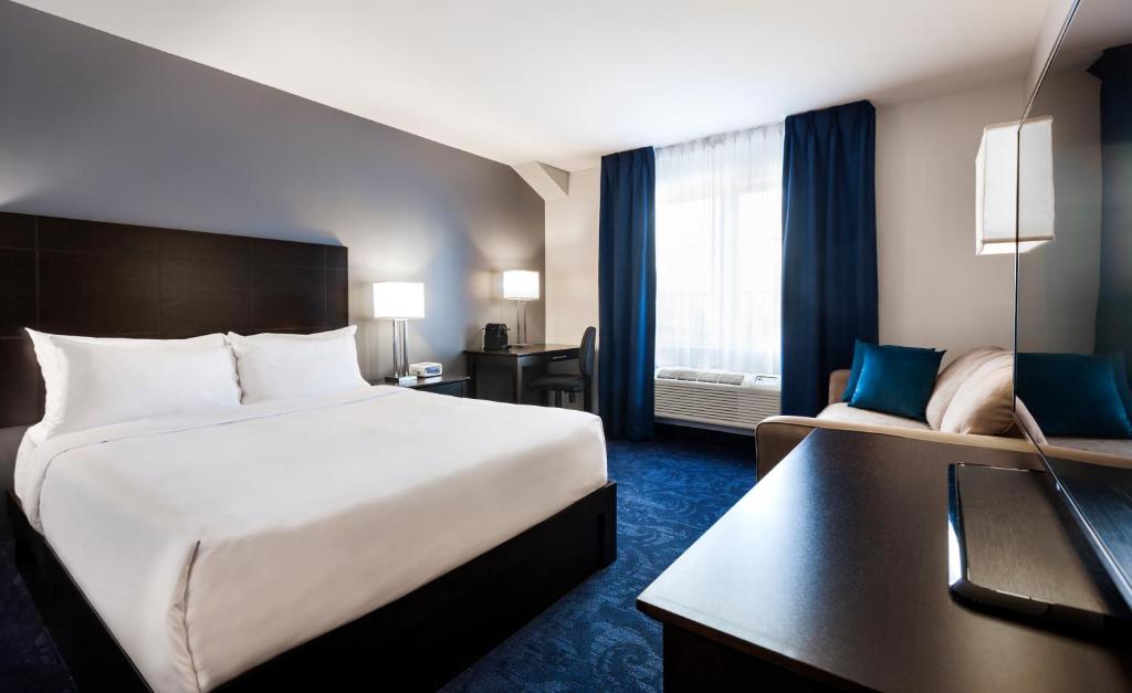 a hotel room with a large bed and a desk at Imperia Hotel & Suites Saint-Eustache in Saint-Eustache