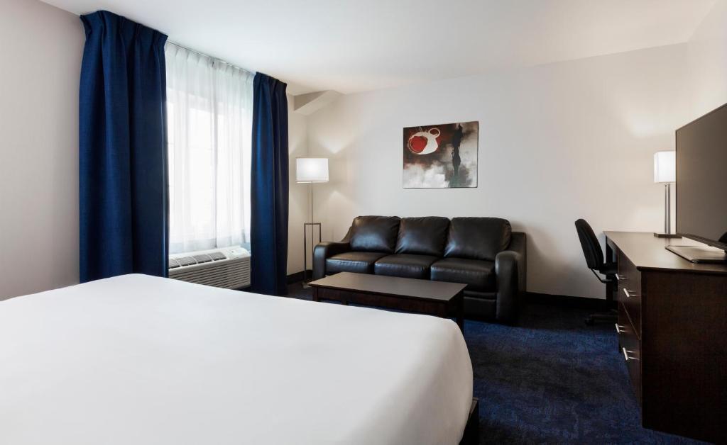 a hotel room with a bed and a couch at Imperia Hotel & Suites Saint-Eustache in Saint-Eustache