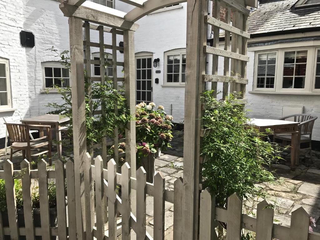 Courtyard Cottages Lymington, 2 Adults only في ليمنجتون: سور أبيض مع بوابة خشبية أمام المنزل