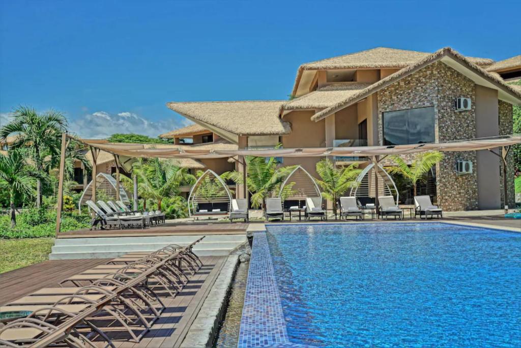 une villa avec une piscine et une maison dans l'établissement Nammbú Beach Front Bungalows, à Sámara