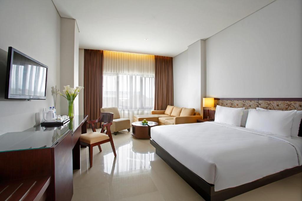 Habitación de hotel con cama y sala de estar. en Hotel Surya Yudha Purwokerto, en Purwokerto