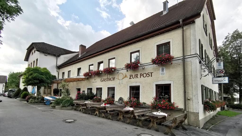 a building with wooden tables in front of it at Gasthof zur Post in Raisting