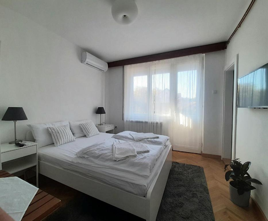 a white bedroom with a bed and a window at Vrnjci House in Vrnjačka Banja