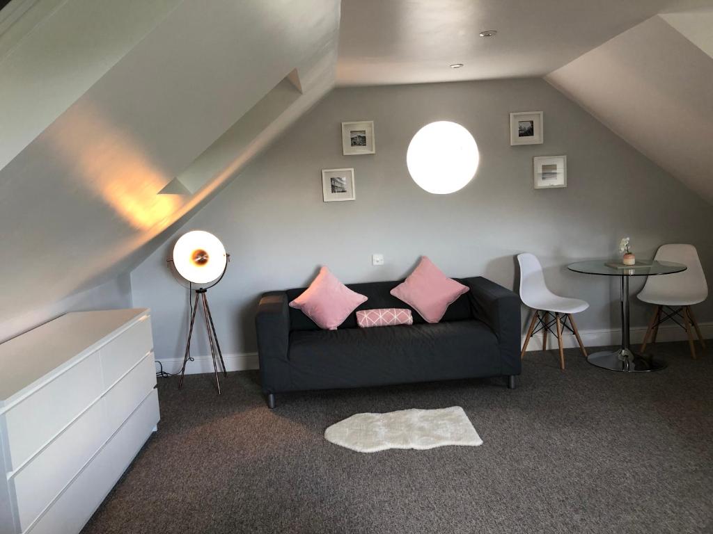 uma sala de estar com um sofá preto e almofadas cor-de-rosa em The Annexe em Bath