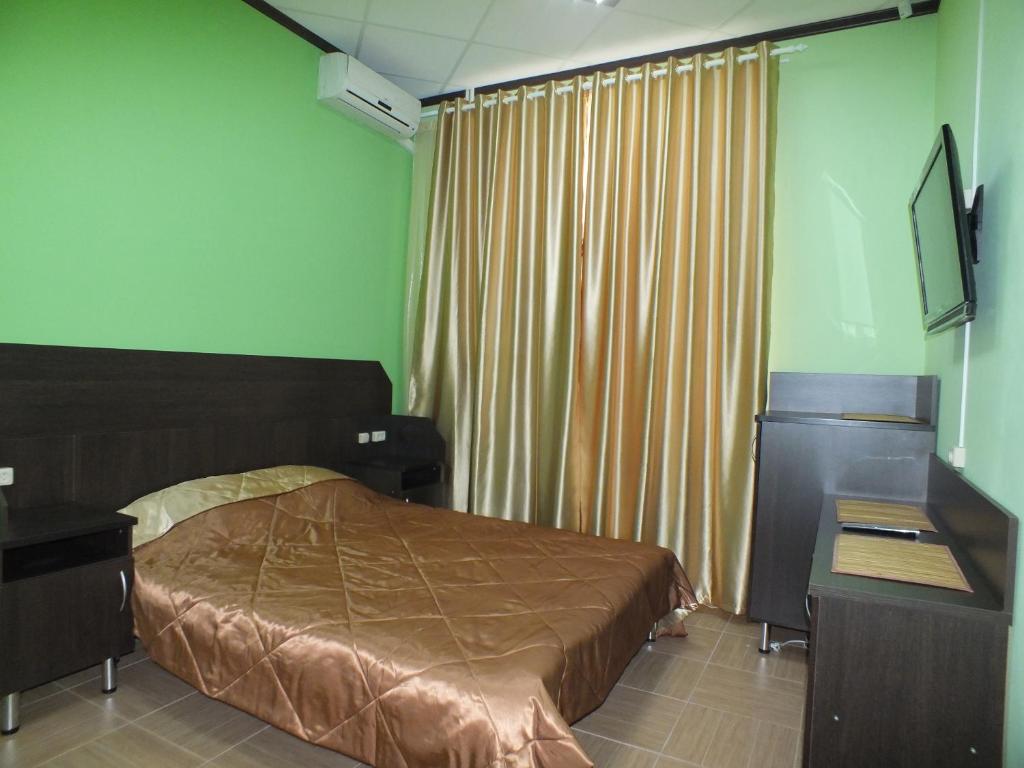 a bedroom with a bed and a desk and curtains at Hotel Persona in Yuzhnoural'sk