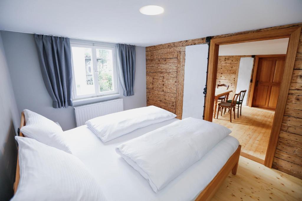 a bedroom with two white beds and a dining room at HEINRICH Stadtwohnung im Jüdischen Viertel in Hohenems