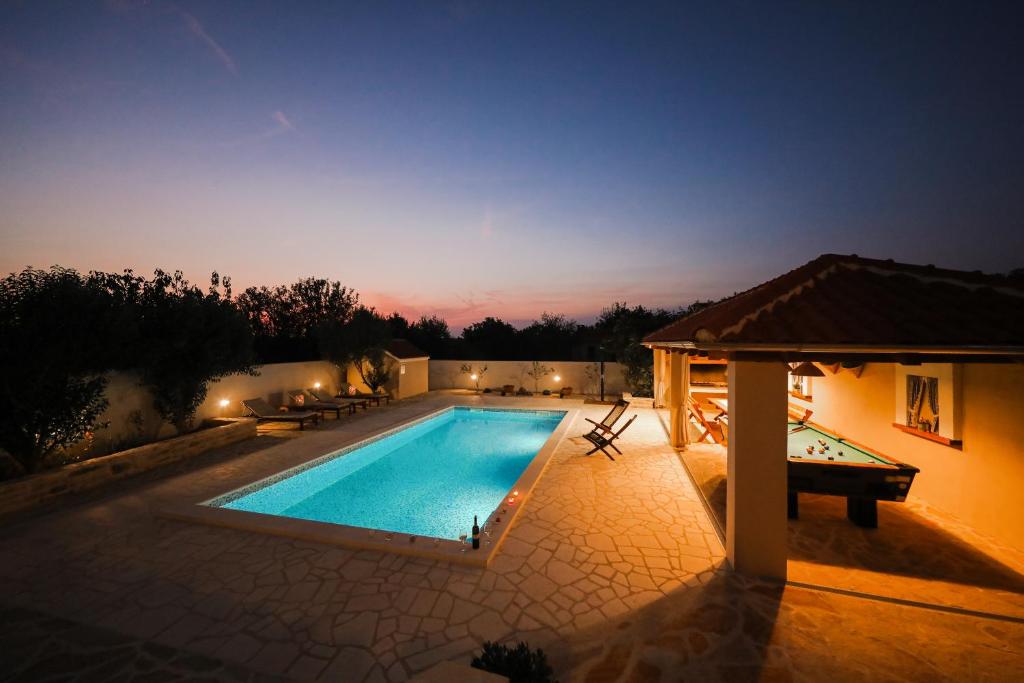 einen Pool mit einer Tischtennisplatte neben einem Haus in der Unterkunft Luka in Pridraga