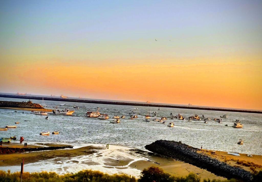 a group of boats in the water at sunset at Estudios Costavigía Mazagón by Ramona in Mazagón