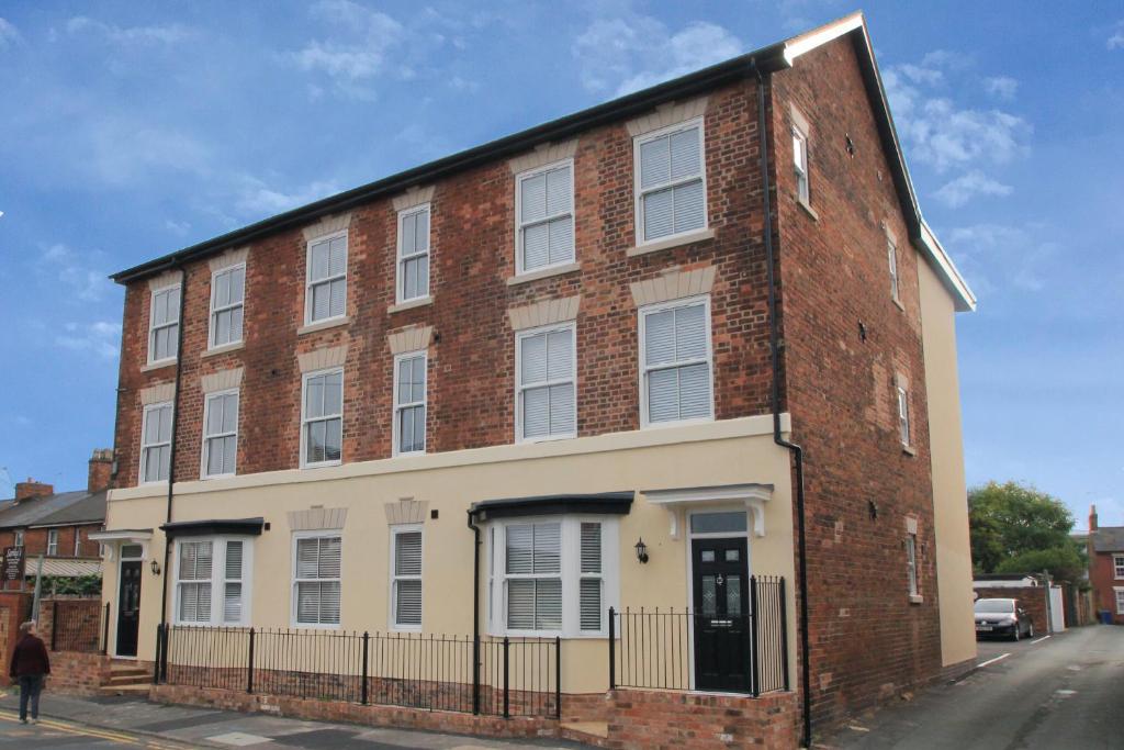 a large brick building with a man walking past it at Friars House, Stafford by BELL Apartments in Stafford