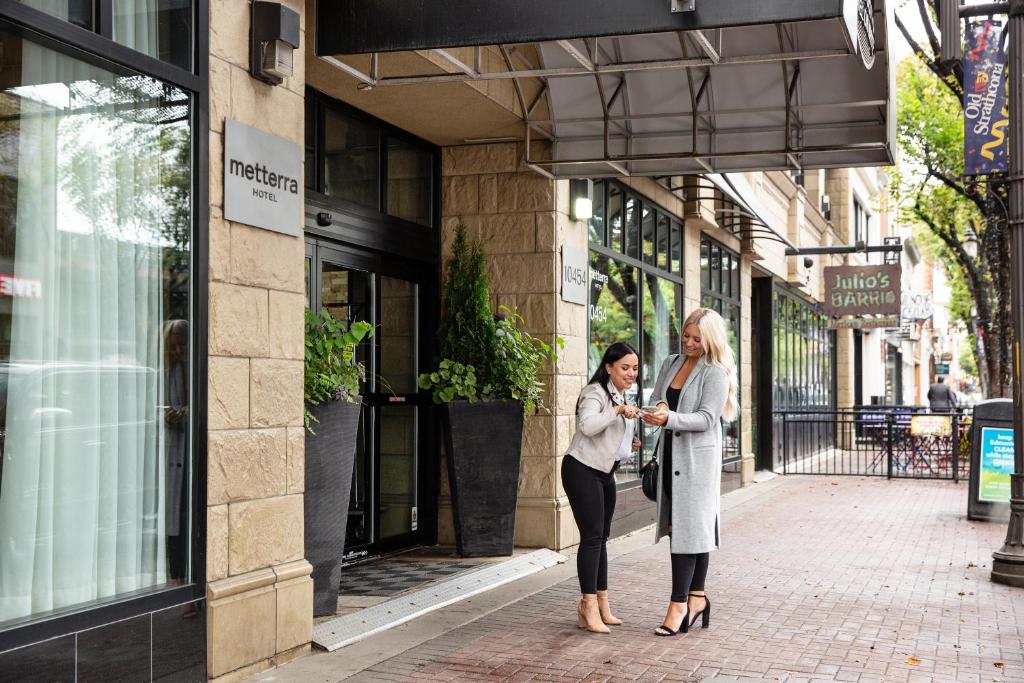 埃德蒙頓的住宿－韋達米特拉酒店，两名妇女站在建筑物前面的人行道上