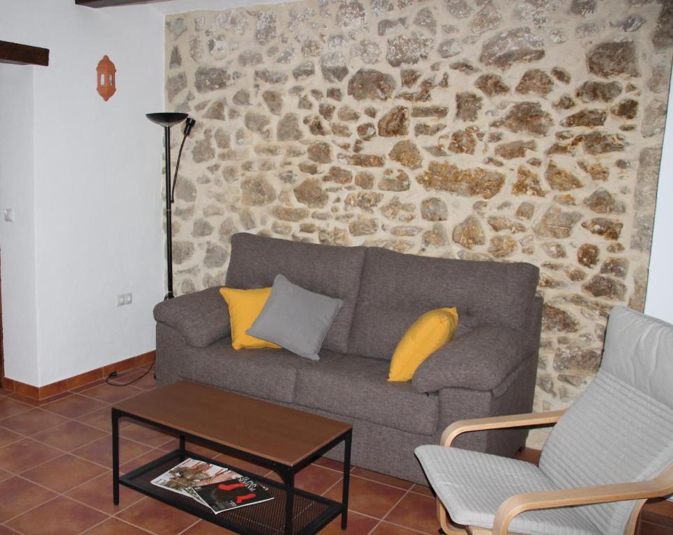 sala de estar con sofá y pared de piedra en CASA RURAL EL ARRIERO, en Zahara de la Sierra