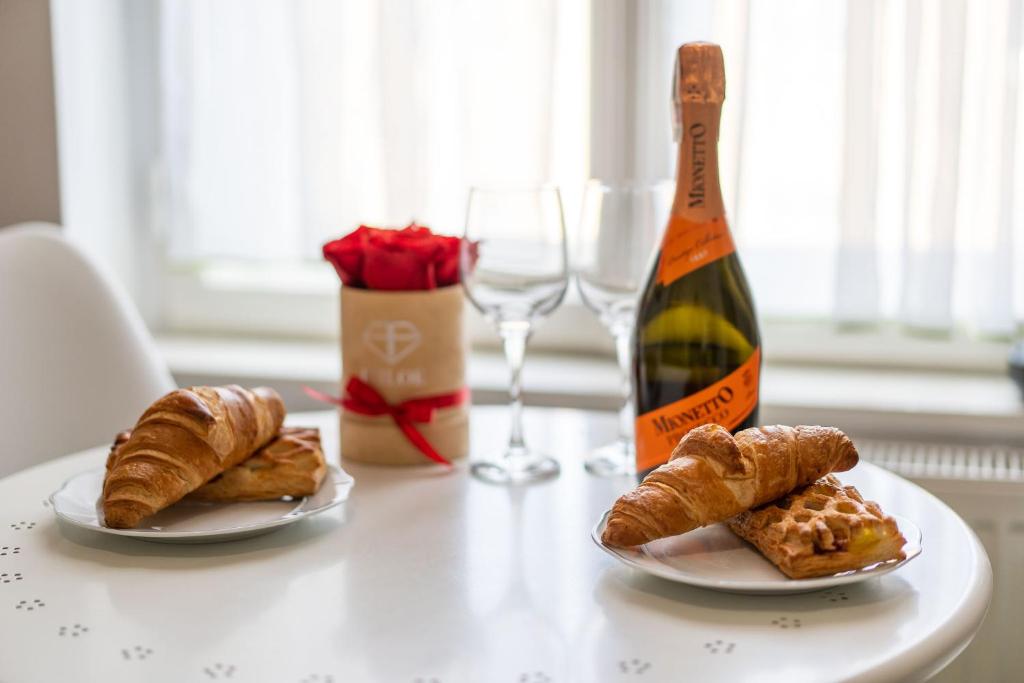 a table with two plates of pastries and a bottle of wine at Apartament Copernicus Olsztyn in Olsztyn