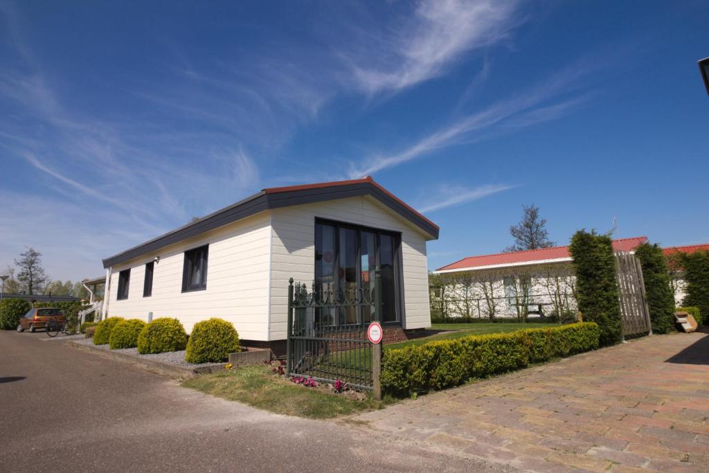 una piccola casa bianca sul lato di una strada di Chaletparc Krabbenkreek Zeeland - Chalet 130 a Sint Annaland