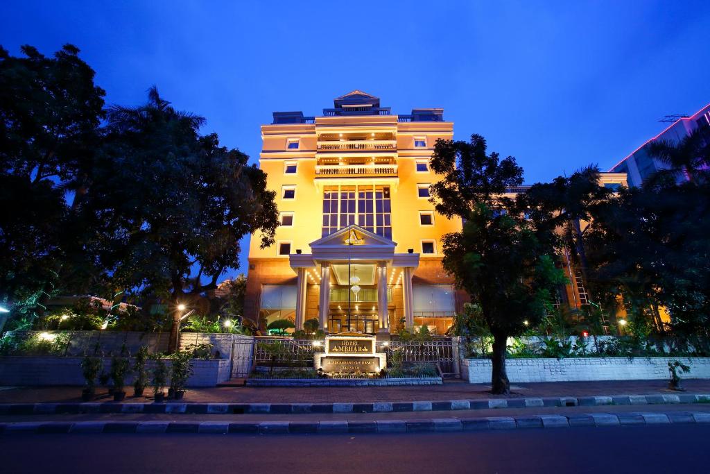 a large yellow building at night with trees in front at Ambhara Hotel in Jakarta