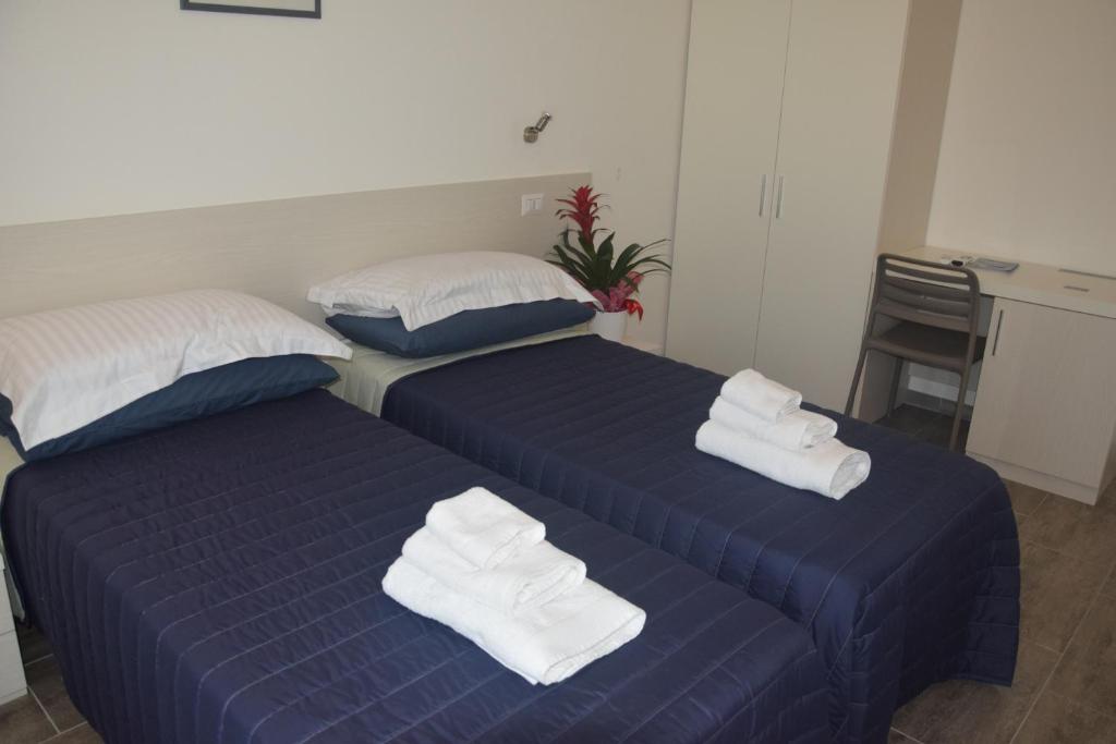 two beds in a room with towels on them at B&B EDEN OGLIASTRA in Tortolì