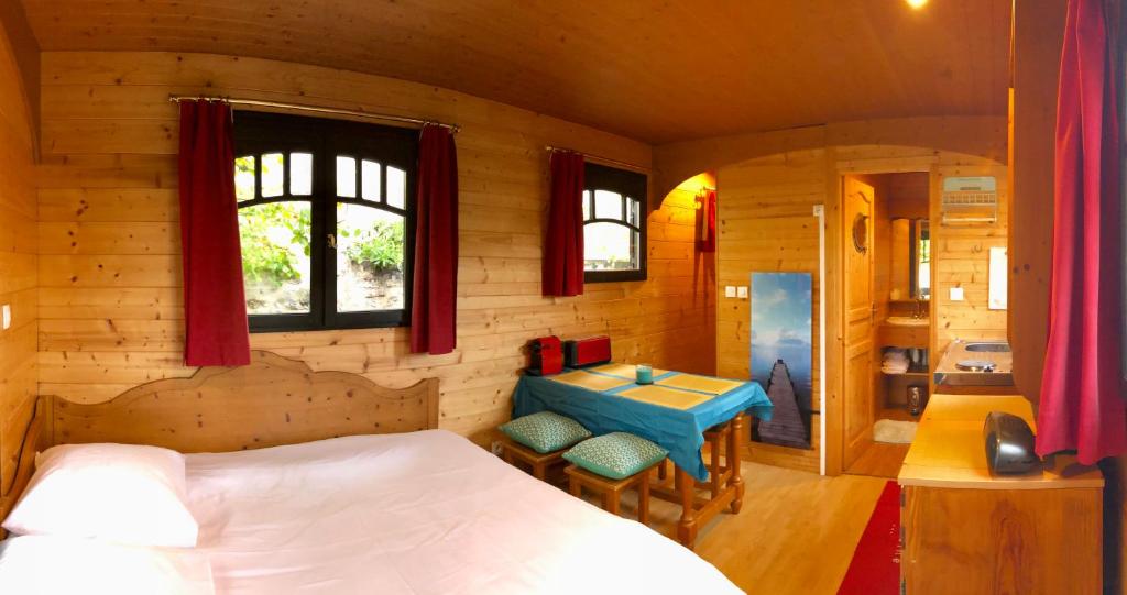 Un dormitorio con una cama y una mesa. en Millygite roulotte - 4 seasons Chalet-on-wheels, en Milly-la-Forêt